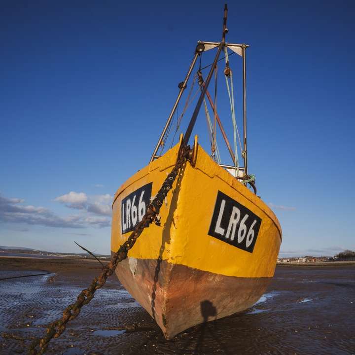 Barco amarelo e preto na areia marrom durante o dia puzzle online