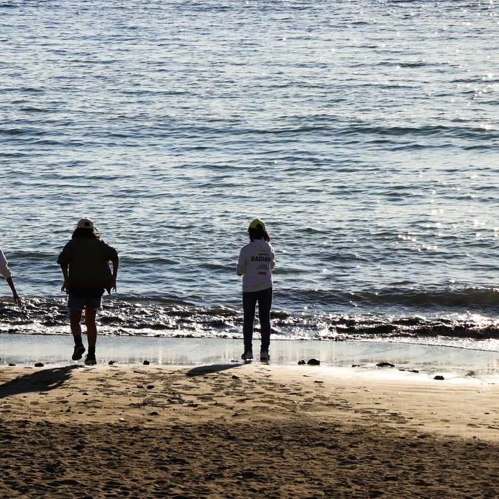 3 hombres de pie en la playa durante el día rompecabezas en línea