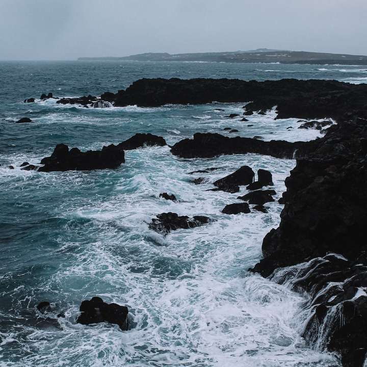 Vlny oceánu narazí na skalách během dne online puzzle