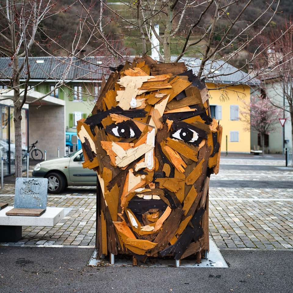 Brązowa drewniana ludzka twarz rzeźbione statua na szarej betonowej drodze puzzle online