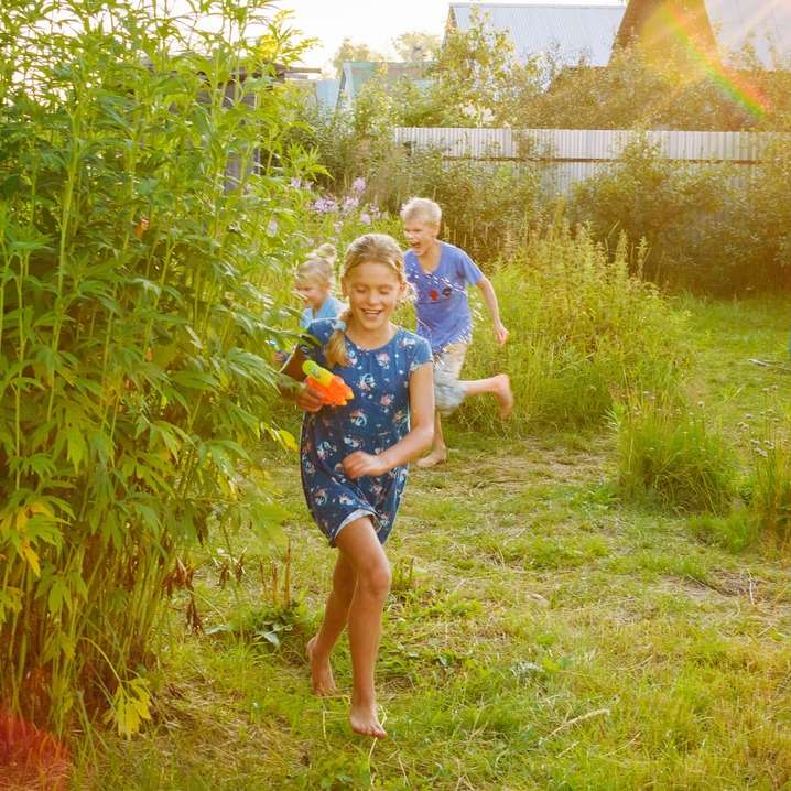 Mädchen im blauen und weißen Hemd, das auf grüner Grasfeld steht Online-Puzzle
