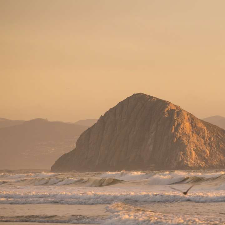 hnědá skalní formace na moři během dne posuvné puzzle online