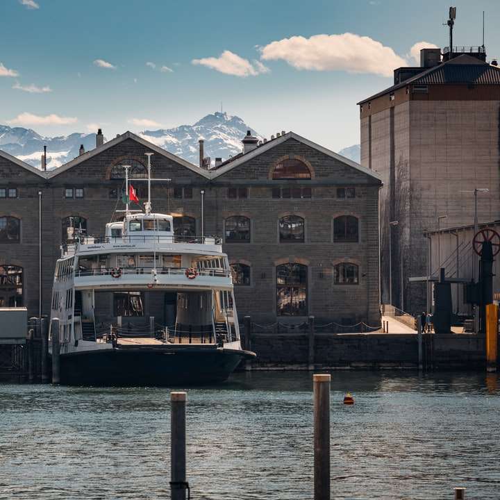 Fehér és fekete csónak a víz közelében barna beton épület csúszó puzzle online