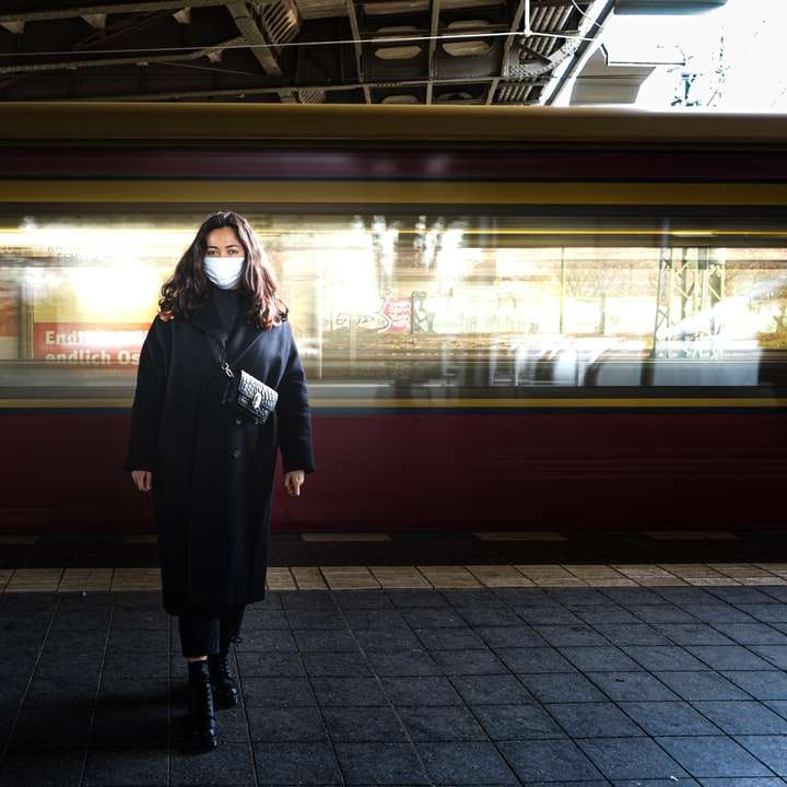 Kvinna i svart långärmad klänning som står på järnvägsstationen glidande pussel online
