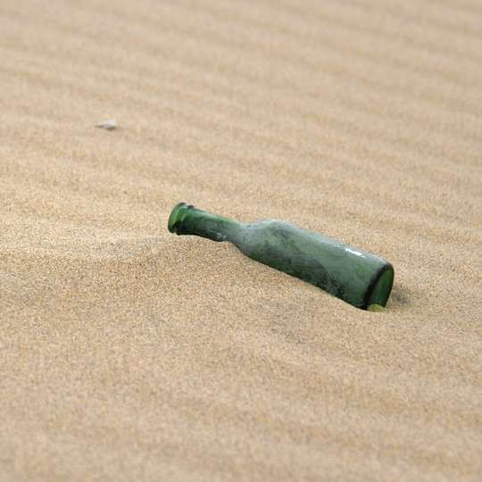 茶色の砂の上の緑と黒のガラス瓶 スライディングパズル・オンライン