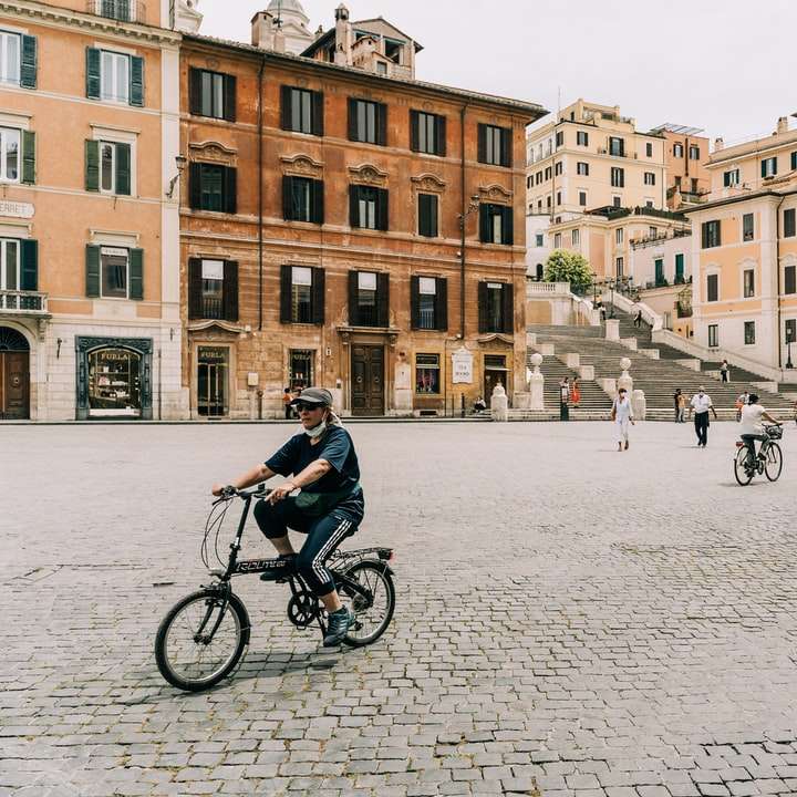 Ludzie jedzie na rowerze na drodze w pobliżu brązowego betonowego budynku puzzle przesuwne online