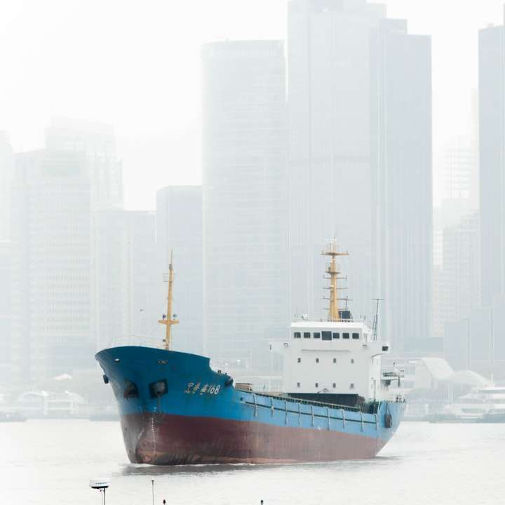 Niebieski i biały statek na białym piasku w ciągu dnia puzzle przesuwne online