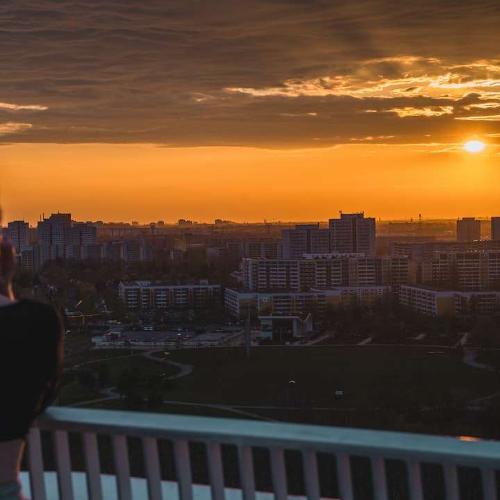 Mulher na camisa preta em pé no balcão durante o pôr do sol puzzle online