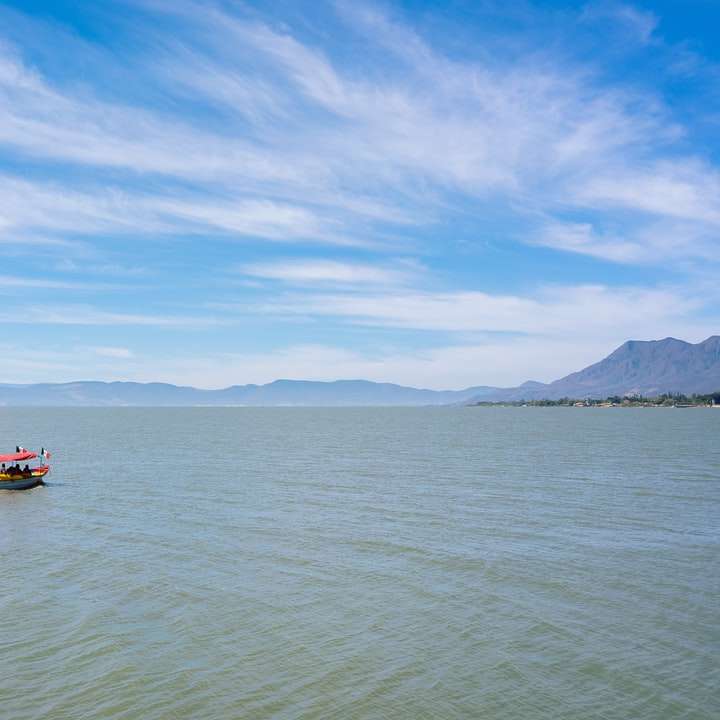 Червена лодка по море под синьо небе през деня онлайн пъзел