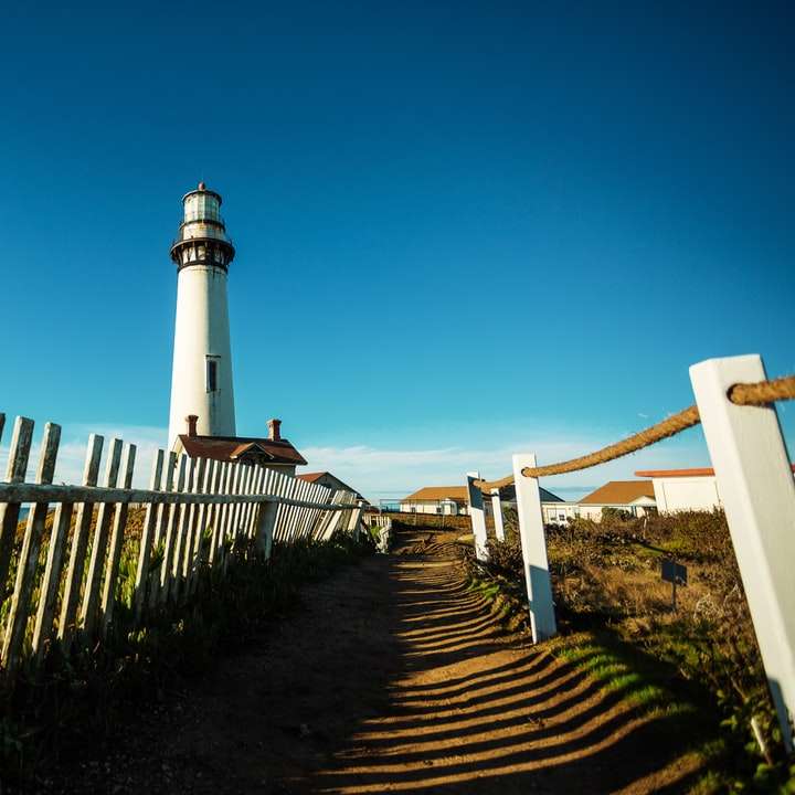 white and black lighthouse near sea under blue sky online puzzle