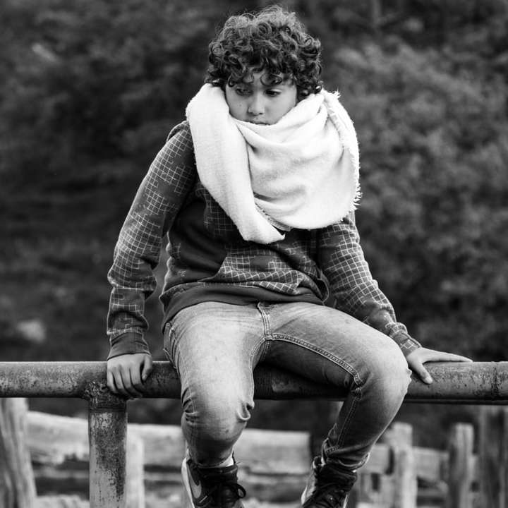 grijswaardenfoto van vrouw zittend op houten hek schuifpuzzel online