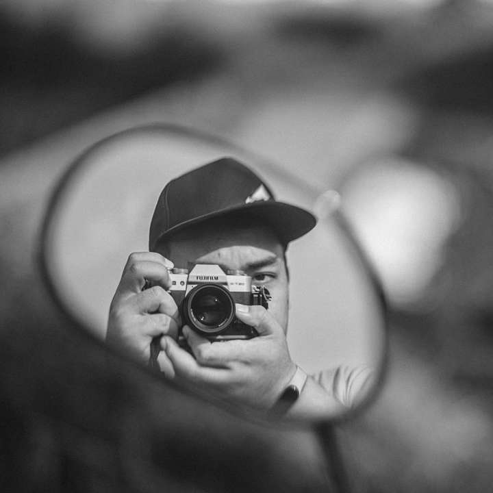 foto in scala di grigi di una persona che tiene in mano la fotocamera puzzle scorrevole online