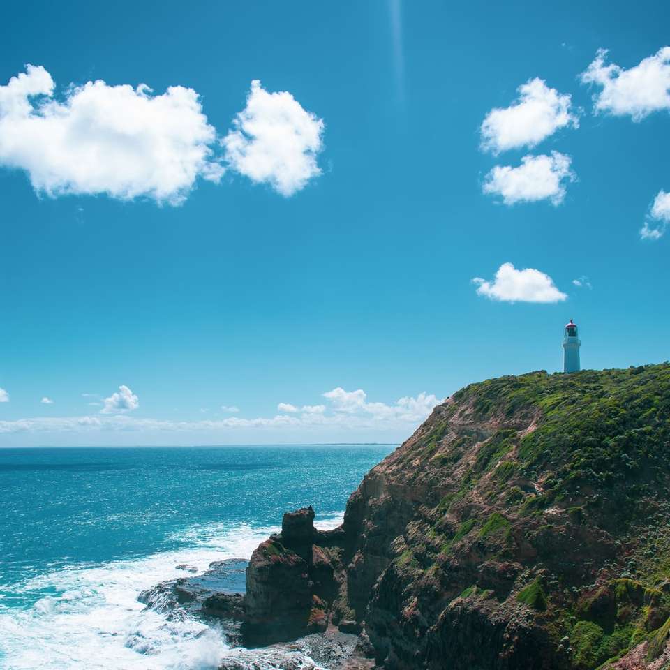 silhouette de phare sur la falaise au bord de la mer puzzle coulissant en ligne