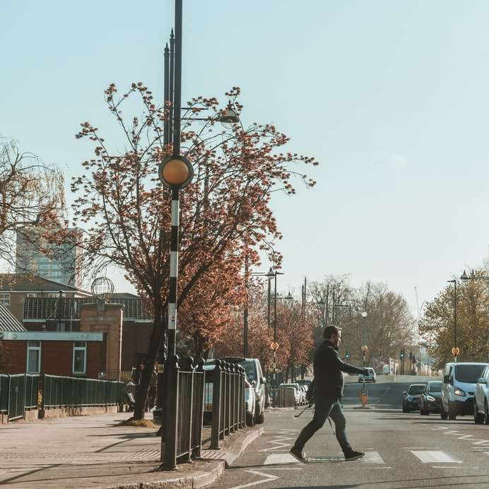 homem de jaqueta preta e calça andando na calçada puzzle online