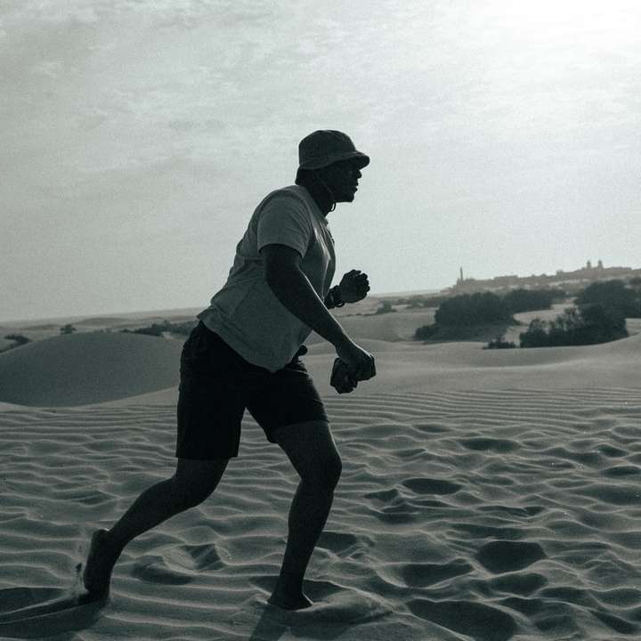 мъж с бяла риза и черни шорти, разхождайки се по плажа плъзгащ се пъзел онлайн