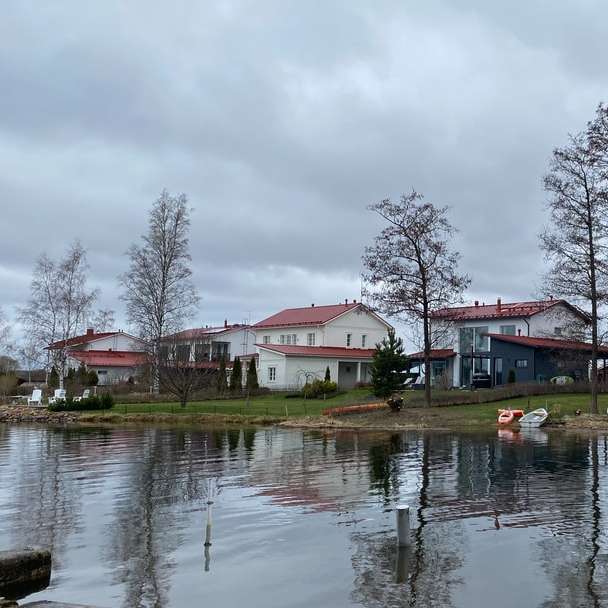 bílý a hnědý dům poblíž vodní plochy pod zataženou oblohou posuvné puzzle online