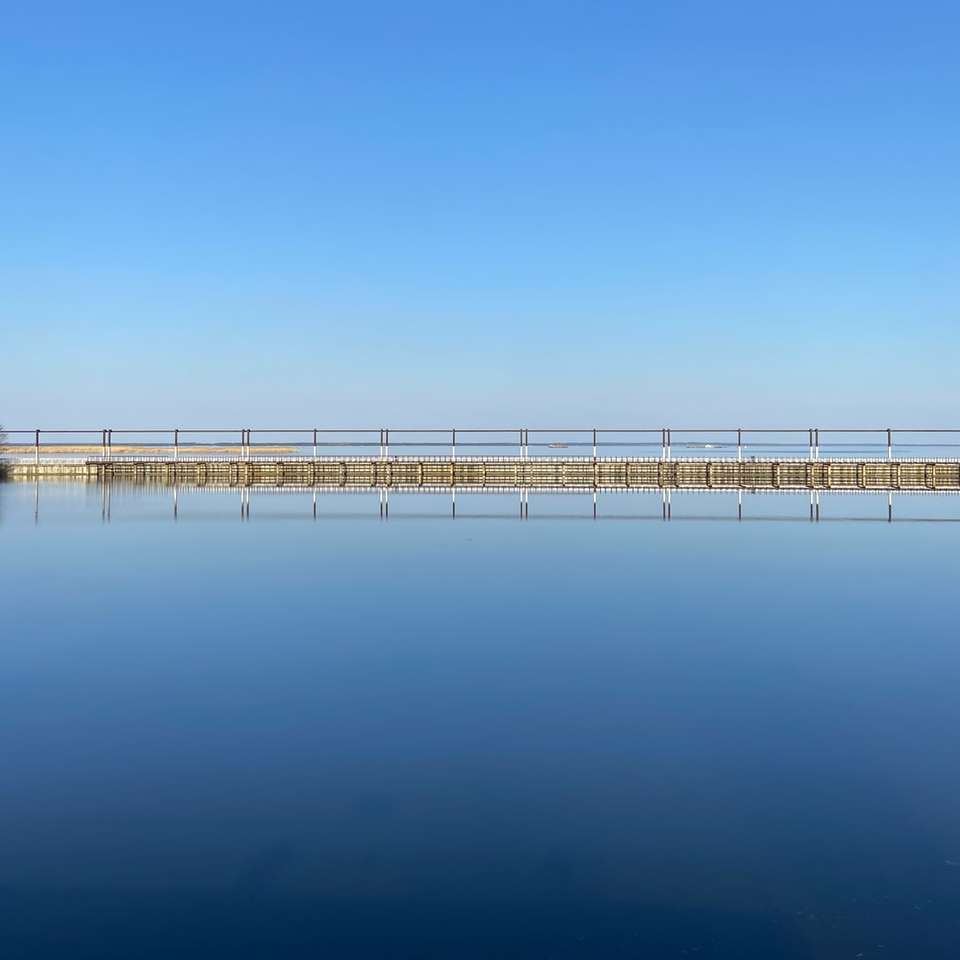 molo di legno bianco su acque calme sotto il cielo blu puzzle scorrevole online