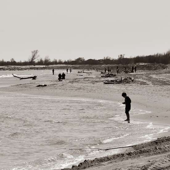 man in zwarte jas lopen op wit zandstrand schuifpuzzel online