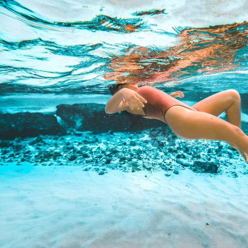 kvinna i blå bikinitrosa simmar i vatten glidande pussel online