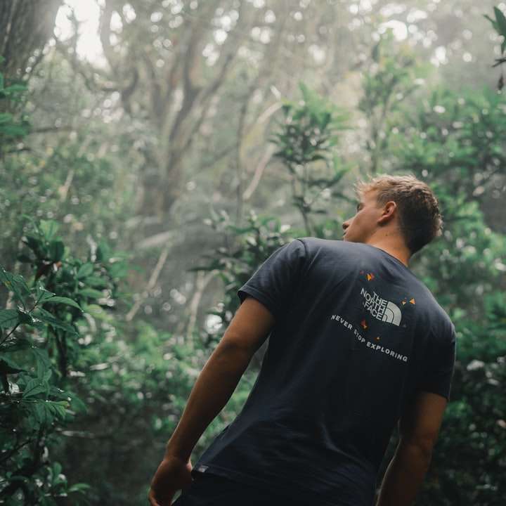 Мужчина в черной футболке с круглым вырезом стоит возле зеленых деревьев онлайн-пазл