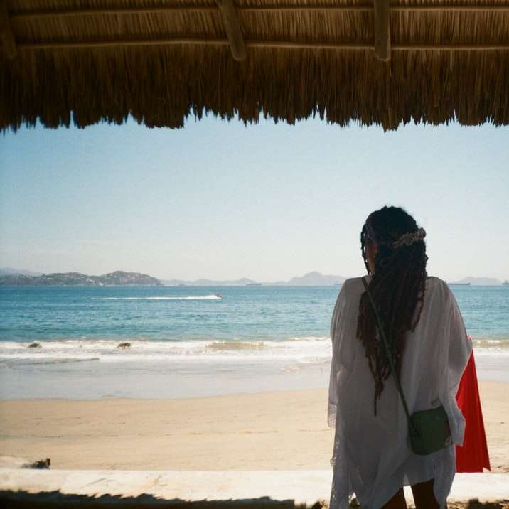 мъж в бяло и червено яке, стоящ на плажа през деня онлайн пъзел
