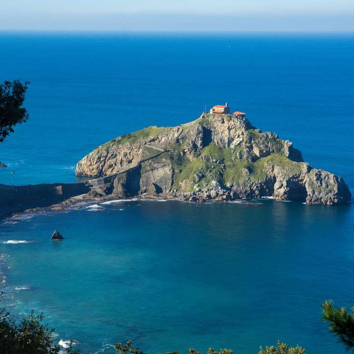 zielona i brązowa góra nad błękitnym morzem w ciągu dnia puzzle przesuwne online