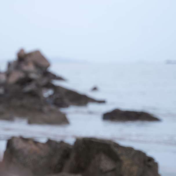 Femme en haut sans manches blanc debout sur le rivage rocheux puzzle coulissant en ligne