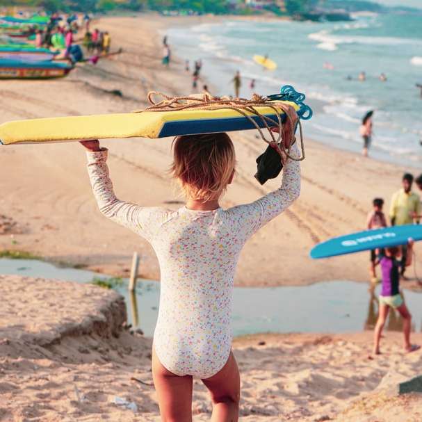 femme en chemise blanche à manches longues tenant une planche de surf marron puzzle en ligne