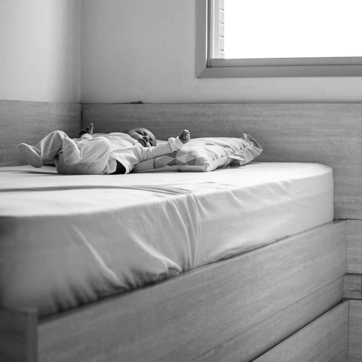 Foto en escala de grises de una mujer acostada en la cama rompecabezas en línea