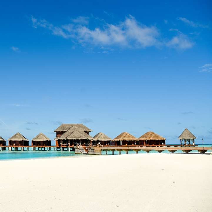 καφέ ξύλινες ομπρέλες παραλίας στην παραλία κατά τη διάρκεια της ημέρας συρόμενο παζλ online