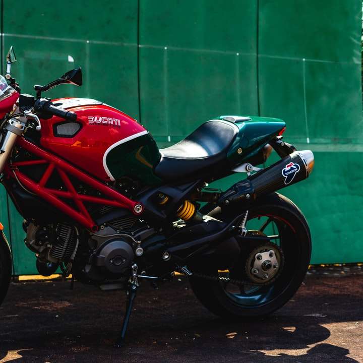 red and black sports bike parked beside green wall online puzzle