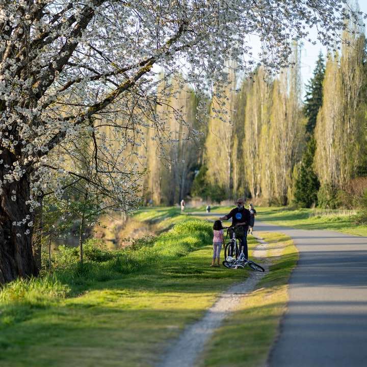 mężczyzna w czarnej kurtce jadący na rowerze na zielonym polu trawy puzzle online