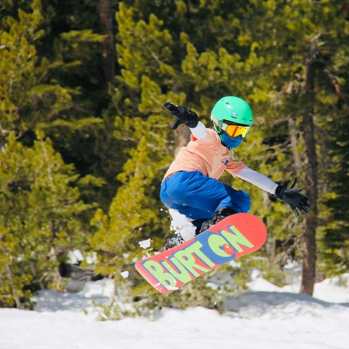 мъж в синьо яке и червена каска, каращ червен сноуборд плъзгащ се пъзел онлайн