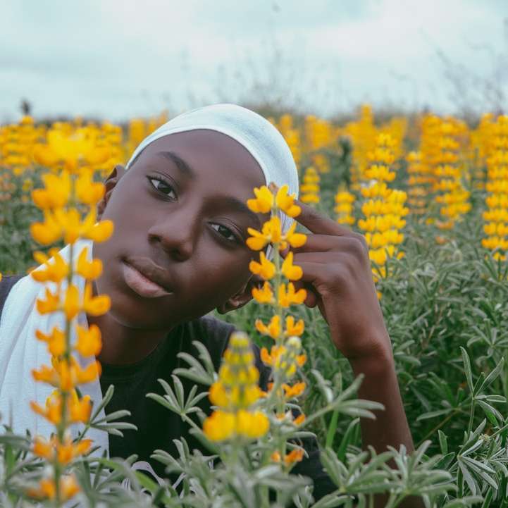 Femme en hijab blanc sur champ de fleurs jaunes pendant la journée puzzle en ligne