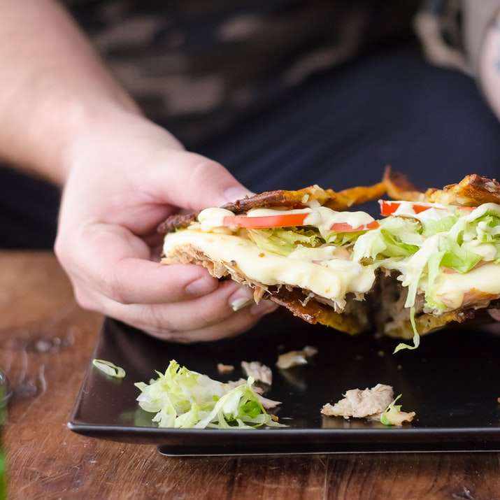 person holding burger with lettuce and tomato online puzzle