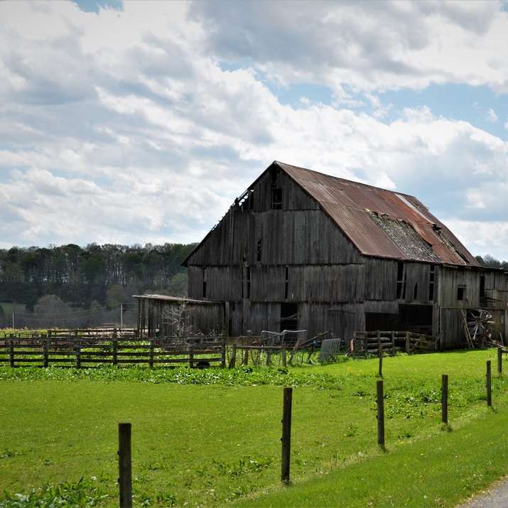 hnědá dřevěná stodola na zelené louce pod bílými mraky online puzzle