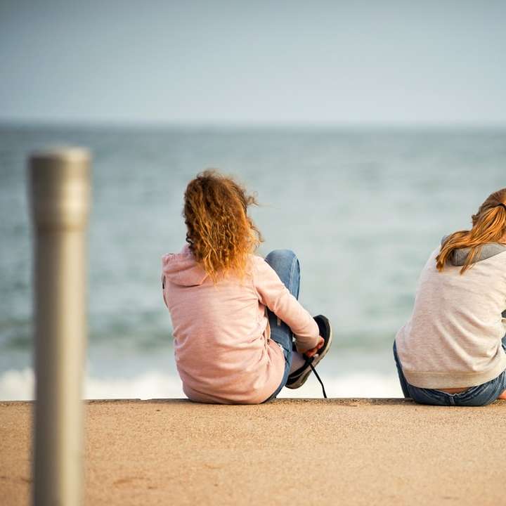 Frau im rosa Langarmhemd sitzt auf braunem Sand Schiebepuzzle online