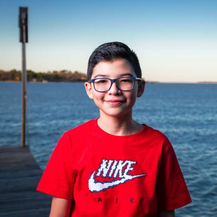 jongen in rood T-shirt met ronde hals en zwarte bril met montuur online puzzel
