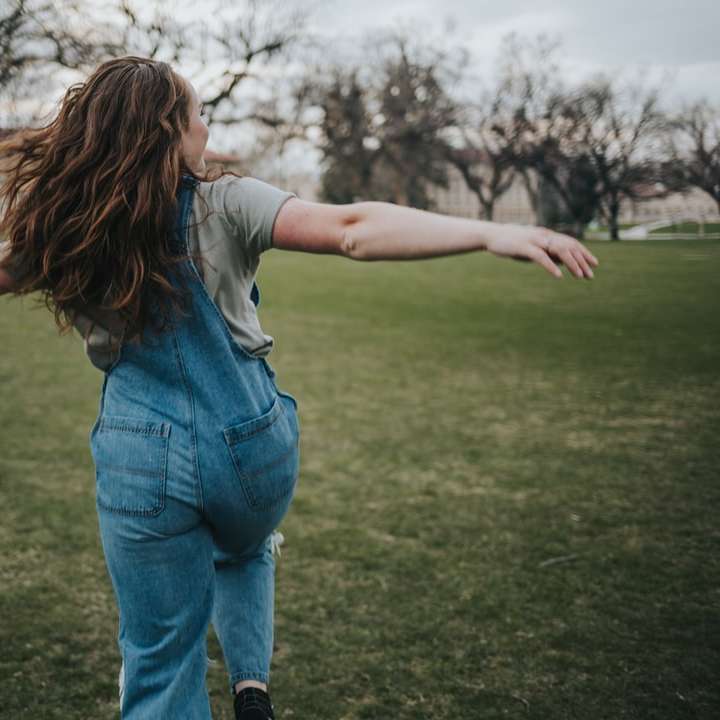 kobieta w niebieskich dżinsach stojąca na zielonym polu trawy puzzle przesuwne online