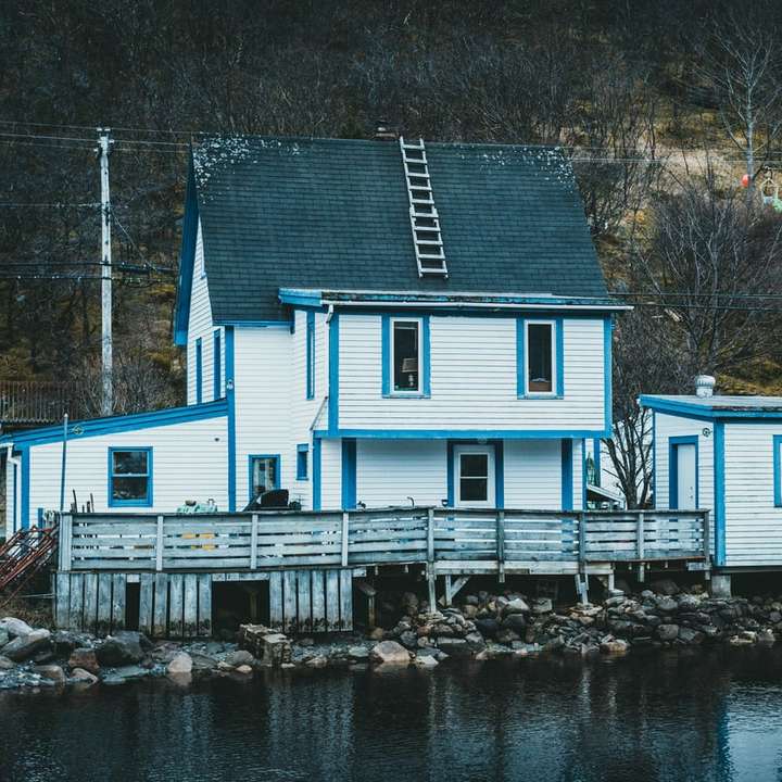 biały i niebieski drewniany dom w pobliżu zbiornika wodnego puzzle przesuwne online