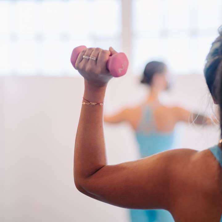 woman in blue tank top holding pink dumbbell sliding puzzle online