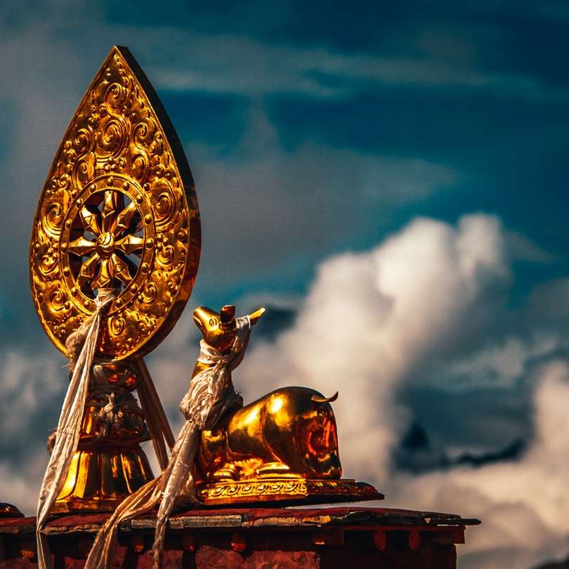 zlatá a zlatá socha draka pod zataženou oblohou během dne posuvné puzzle online