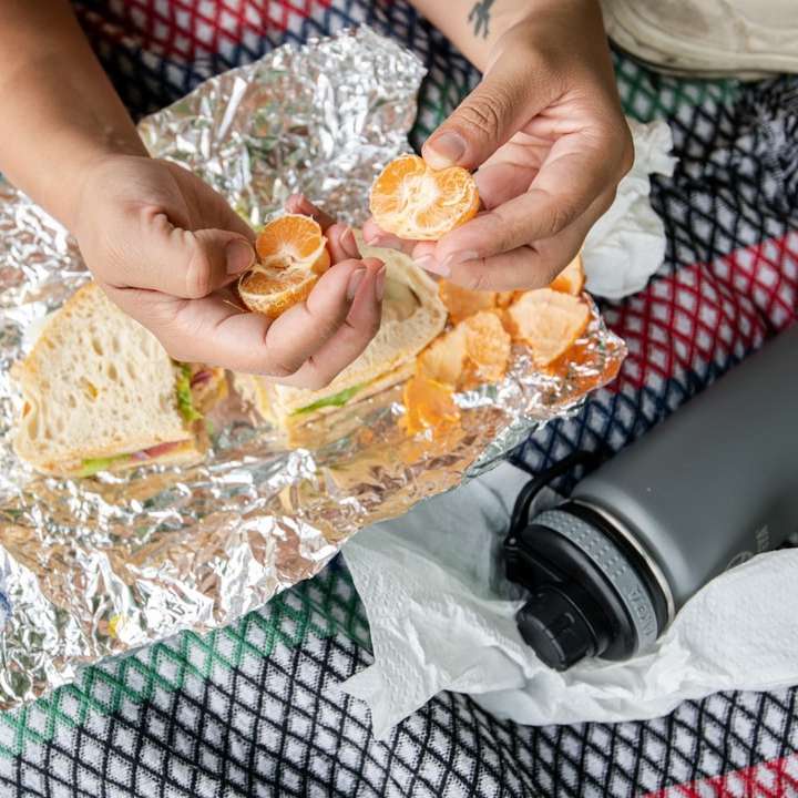 pessoa segurando pão integral com laranja em cima puzzle online