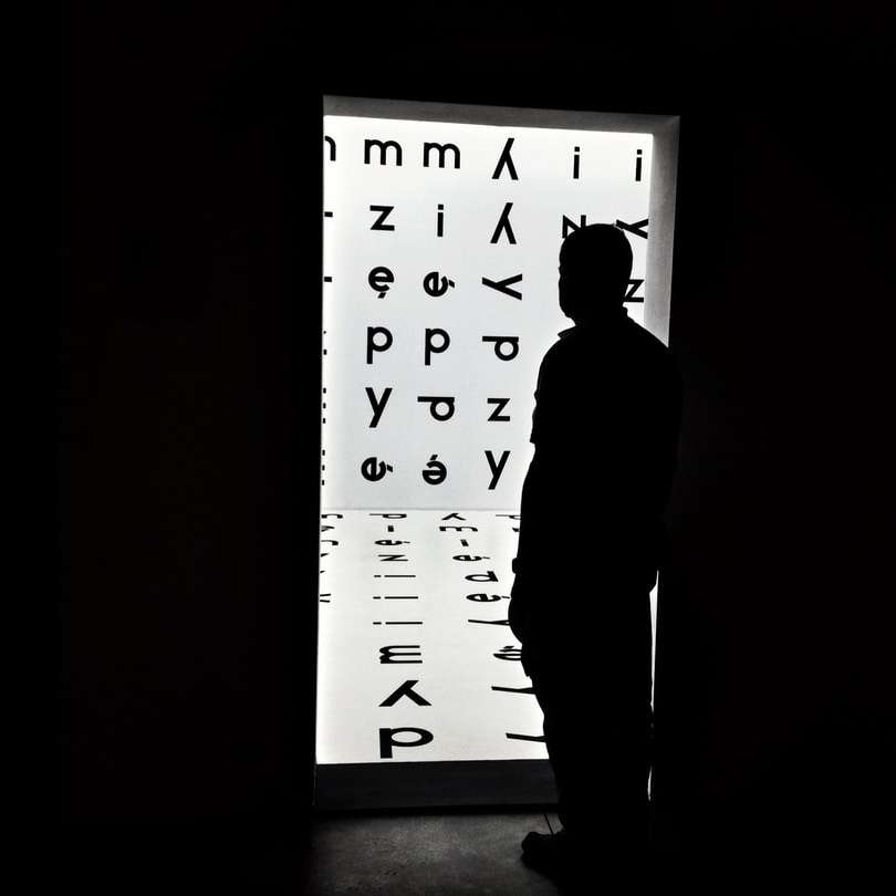 白と黒の壁の前に立っている男のシルエット スライディングパズル・オンライン