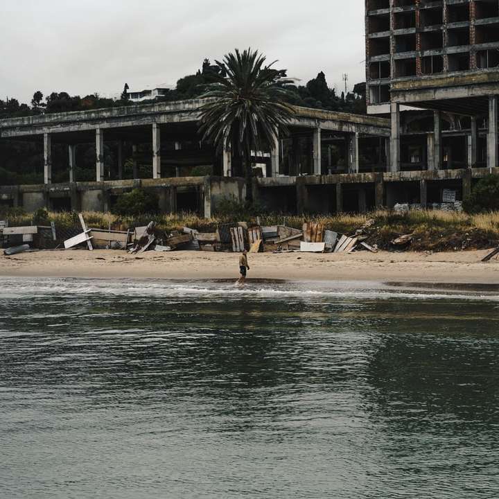 хора, които се разхождат по брега на плажа близо до сградата през деня онлайн пъзел