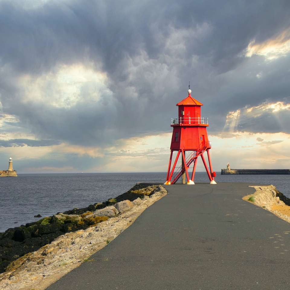 red and white lighthouse near body of water online puzzle