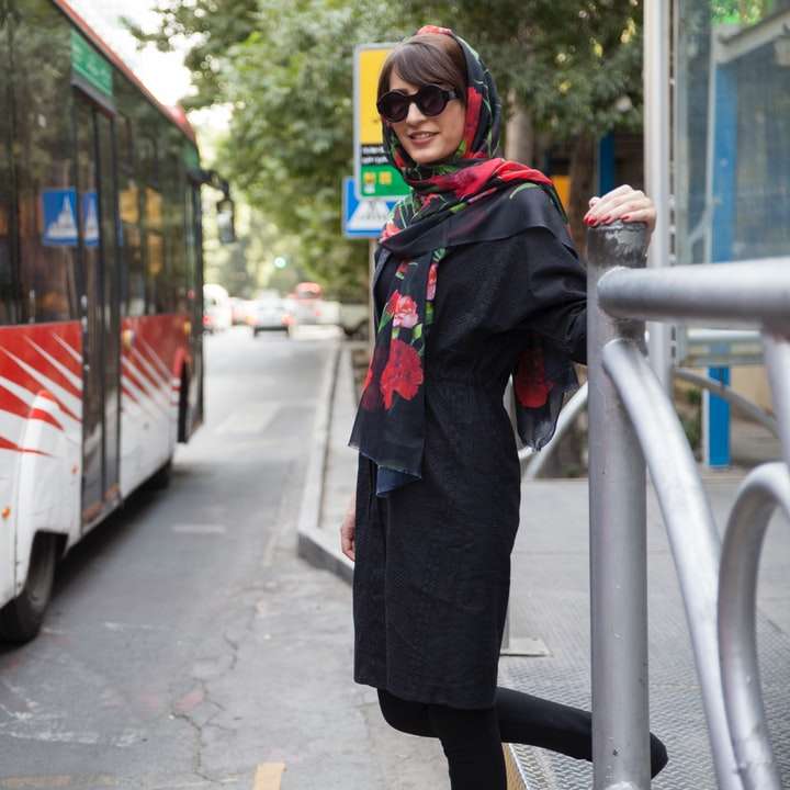 Frau in schwarzer Jacke, die in der Nähe des roten und weißen Busses steht Schiebepuzzle online
