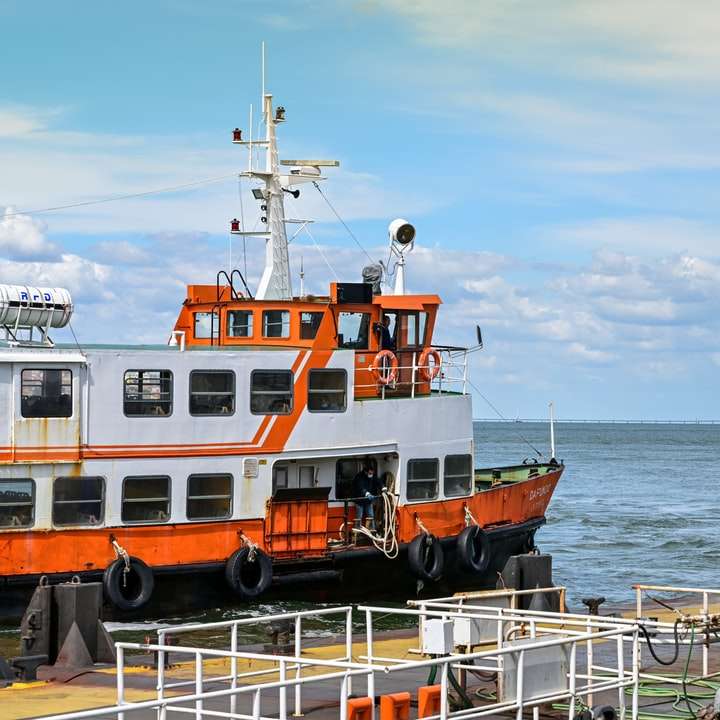 oranje en wit schip op zee overdag schuifpuzzel online