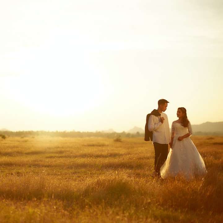 Hombre y mujer caminando sobre el campo de hierba marrón durante el día puzzle deslizante online