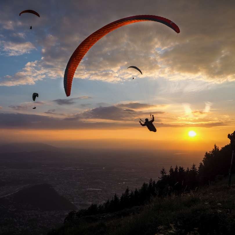 sziluettje az emberek lovaglás ejtőernyős naplemente alatt online puzzle